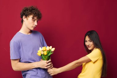 Şirin genç bir çift, sarı çiçekli bir buket arkadaşlığa dayalı değişmemiş bir arka plan.