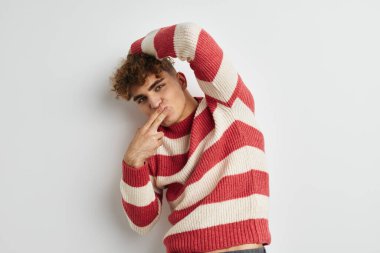 Çizgili kazaklı, değişmemiş yaşam tarzı pozu veren tuhaf bir adam.