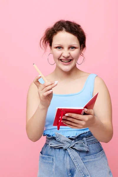 Aantrekkelijke vrouw schrijven in een rode notebook met een pen studie roze kleur achtergrond ongewijzigd — Stockfoto