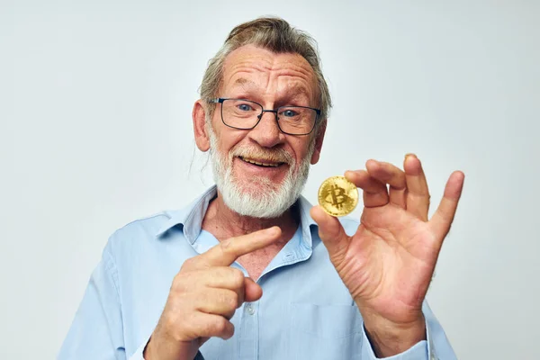 Mavi gömlekli emekli yaşlı bir adamın fotoğrafı. Arka planda Bitcoin var.