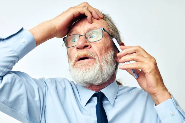 Starý muž s telefonem šokován ve studiu na bílém pozadí — Stock fotografie
