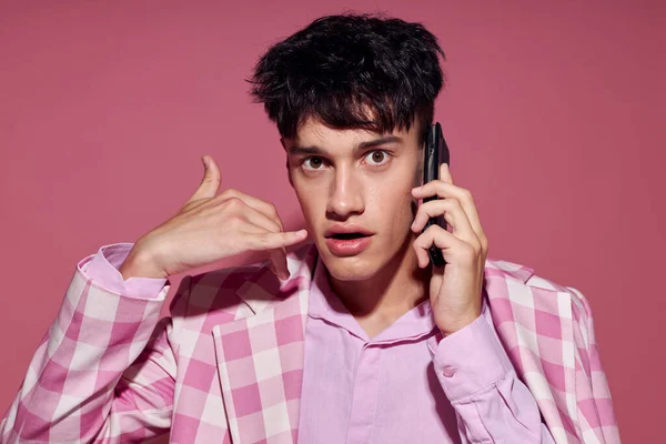 한 젊은 남성 이 아무런 변화 없이 스튜디오 핑크 색 배경을 꾸미며 전화 통화를 하고 있습니다. — 스톡 사진