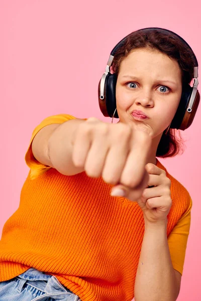 Mulher bonita grimace fones de ouvido entretenimento emoções música rosa fundo inalterado — Fotografia de Stock