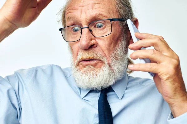 Anciano con teléfono impactado en el estudio sobre fondo blanco —  Fotos de Stock