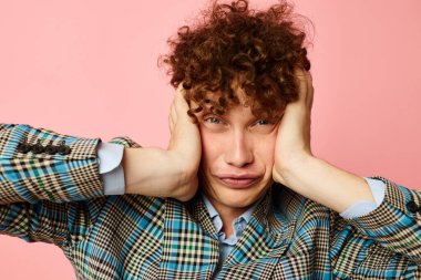 Takım elbiseli, kızıl kıvırcık saçlı adam duygularını belli ediyor pembe arka plan değişmemiş.