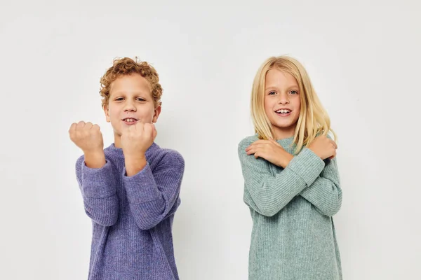 Jongen en meisje in multi-gekleurde truien poseren voor plezier lichte achtergrond — Stockfoto