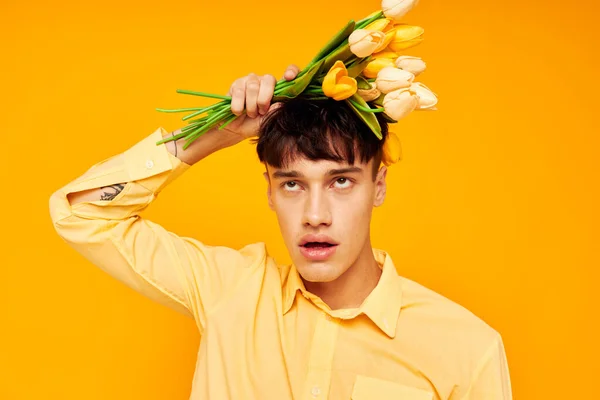 Hombre bonito en gafas amarillas con un ramo de flores fondo amarillo inalterado — Foto de Stock