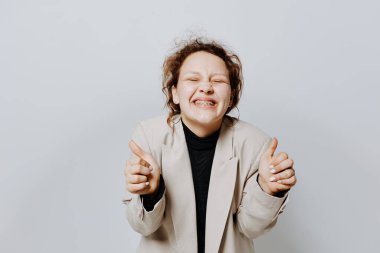 Hafif, klasik bir takım elbiseyle neşeli bir kadın. Duygularını belli ediyor. Arka planda değişiklik yok.