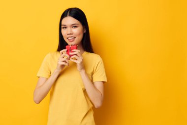 Sarı tişörtlü bayram hediyesi giymiş bir kadın. Duyguları değişmemiş stüdyo modeli.