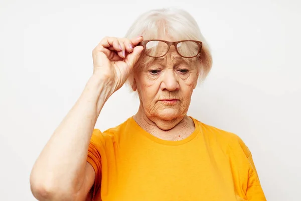Foto de anciana jubilada en camiseta casual y gafas de fondo aislado — Foto de Stock