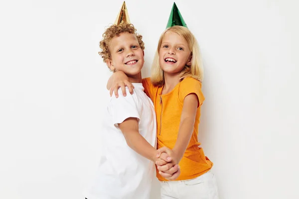 Fiú és lány pózol érzelmek ünnep színes sapkák elszigetelt háttér változatlan — Stock Fotó