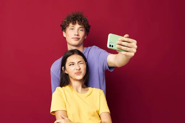 Una giovane coppia stile moderno emozioni divertimento telefono rosso sfondo — Foto Stock
