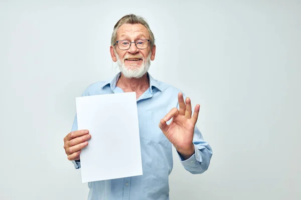 Старший седой мужчина чистый лист бумаги жест руки улыбаются светлый фон — стоковое фото