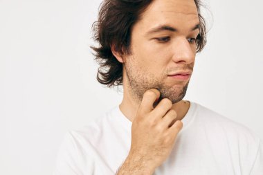 Beyaz tişörtlü yakışıklı adam telefonla iletişim kuruyor. Yaşam tarzı değişmemiş.