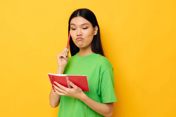 Charmant jeune asiatique femme vert T-shirts avec carnet rouge et stylo fond isolé inaltéré — Photo