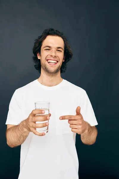 Чоловік склянка води в руках емоції позує бежевий фон — стокове фото