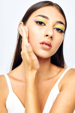 Güzel, esmer, beyaz tişörtlü el hareketleri çekici, hafif arka planda değişiklik yok.