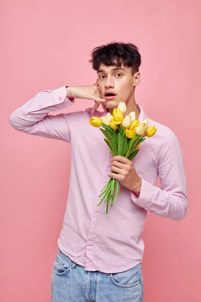 Фото романтичного молодого хлопця Буке з жовтими квітами романтика, що видає модний рожевий фон незмінним. — стокове фото