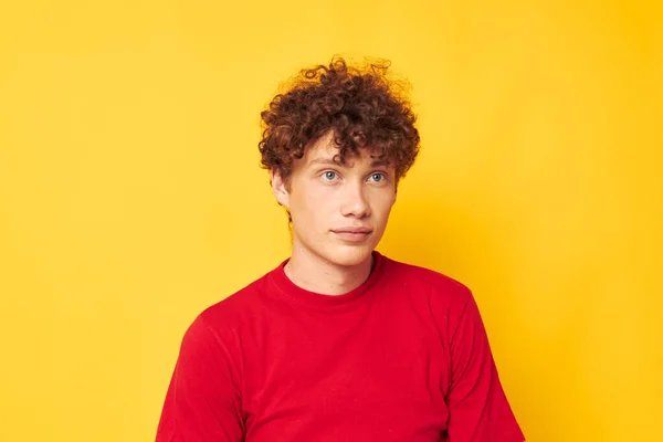 Joven rizado hombre rojo camiseta divertido posando casual desgaste amarillo fondo inalterado — Foto de Stock