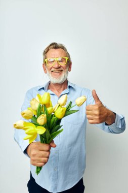 Yaşlı bir adam bir buket çiçek ve hediye olarak hafif bir arka plan.