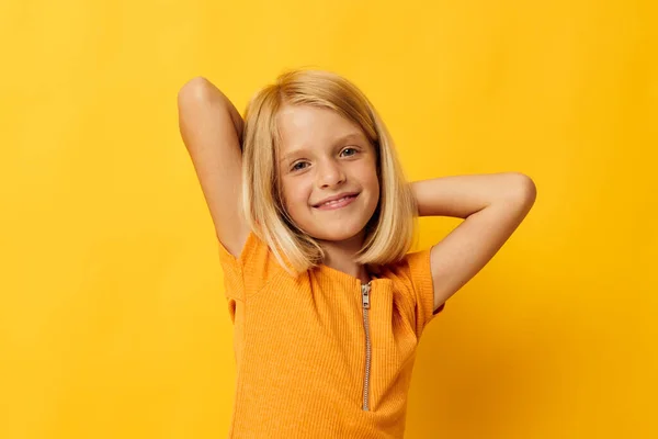 Cute little girl uśmiech strony gesty pozowanie casual nosić zabawy żółty tło bez zmian — Zdjęcie stockowe