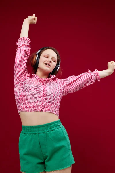 Χαριτωμένο νεαρό κορίτσι σε πολύχρωμα ρούχα θέτοντας μουσική με τα ακουστικά αναλλοίωτα — Φωτογραφία Αρχείου