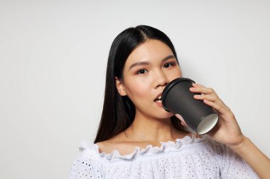 Tek kullanımlık bir bardak içecekle poz veren bir kadın.