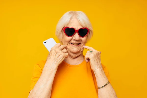 Yüzü somurtkan yaşlı bir kadının portresi. Elinde telefon, kırpılmış bir manzara. — Stok fotoğraf