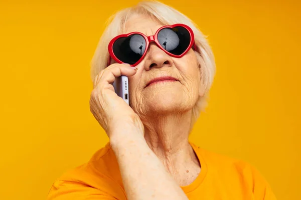 Emekli yaşlı kadının mutlu bir hayat tarzı var. Sarı tişörtlü, dürbünlü gözlüklü. — Stok fotoğraf