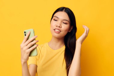 Asyalı güzel bir kadının portresi. Elinde telefon olan güzel bir kadın. İzole edilmiş bir özçekim yapıyor.
