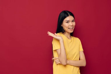 Kadın, elleri sarı tişörtlü, jestler yapar. Günlük kıyafetlerini giyer, yaşam tarzını değiştirmez.