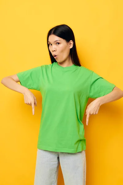 Bonita morena posando em verde t-shirt emoções cópia-espaço amarelo fundo inalterado — Fotografia de Stock