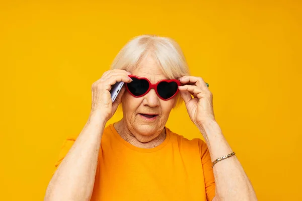 Portret van een oude vriendelijke vrouw poseren gezicht grimas met een telefoon in de hand bijgesneden uitzicht — Stockfoto