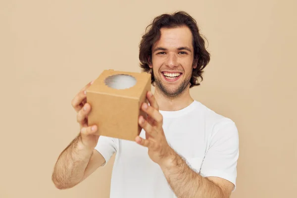 Веселий чоловік у білій футболці з подарунковою коробкою — стокове фото