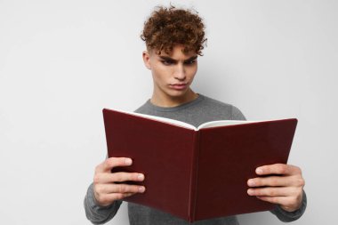 Kitap eğitimi almış genç bir çocuk poz veriyor.