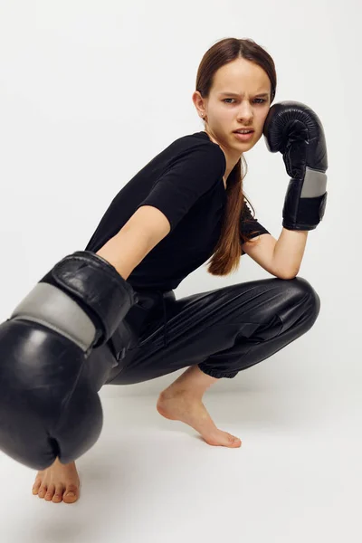 Menina bonita em luvas de boxe no chão em preto t-shirt luz fundo — Fotografia de Stock