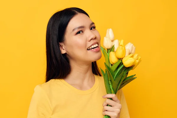 노란 꽃 꽃다발을 들고 있는 아시아인아름다운 젊은 여자의 모습은 변함 이 없는 배경으로 외따로 떨어져 있다 — 스톡 사진