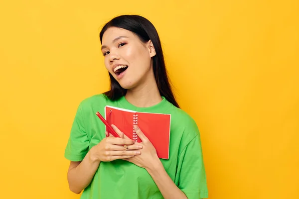 Charmant jeune asiatique femme vert T-shirts avec carnet rouge et stylo fond isolé inaltéré — Photo