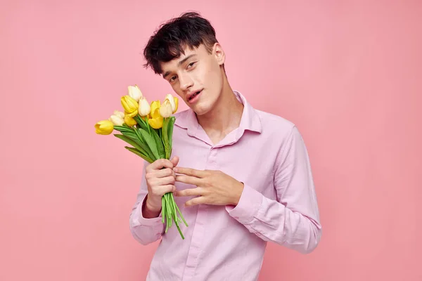 Фото романтичного молодого хлопця Буке з жовтими квітами романтика, що видає модний рожевий фон незмінним. — стокове фото
