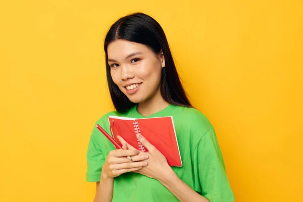 Charmant jeune asiatique femme vert T-shirts avec carnet rouge et stylo fond isolé inaltéré — Photo