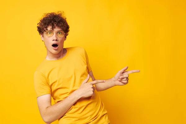 Jeune homme aux cheveux bouclés portant des lunettes élégantes t-shirt jaune posant fond isolé inaltéré — Photo