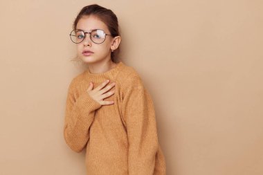 Süveter giyen ve gözlük takan mutlu gülümseyen kız çocuğu portresi.