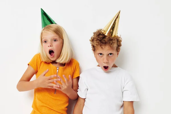 Два радостных детей, представляющих эмоции праздник красочные колпачки светлый фон — стоковое фото