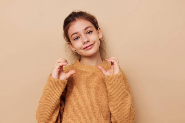 Портрет щасливої усміхненої дівчинки в светрі, що позує руками жести дитинства незмінними — стокове фото