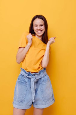 Sarı tişörtlü iyimser genç bir kadın. Yaz tarzı sarı arka plan.