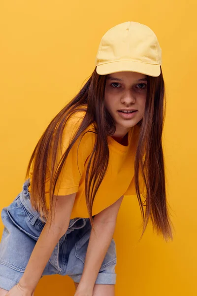 Photo pretty woman posing in a yellow T-shirt and cap isolated background — Fotografia de Stock