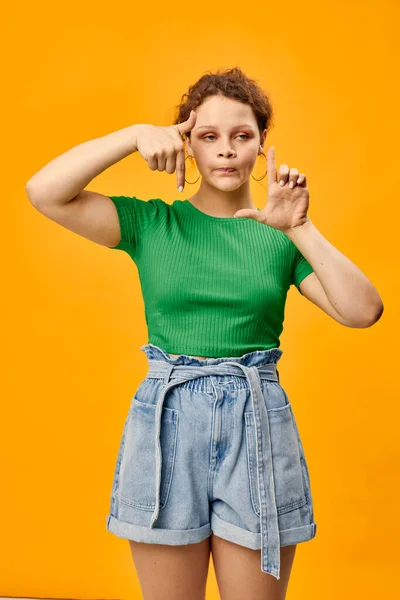 Menina alegre em um verde t-shirt posando gesto mãos amarelo fundo — Fotografia de Stock