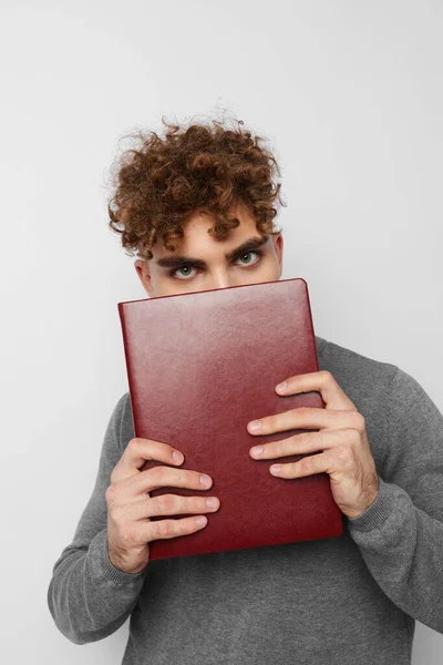 Roztomilý chlap s kudrnatými vlasy s knihou v ruce trénink — Stock fotografie