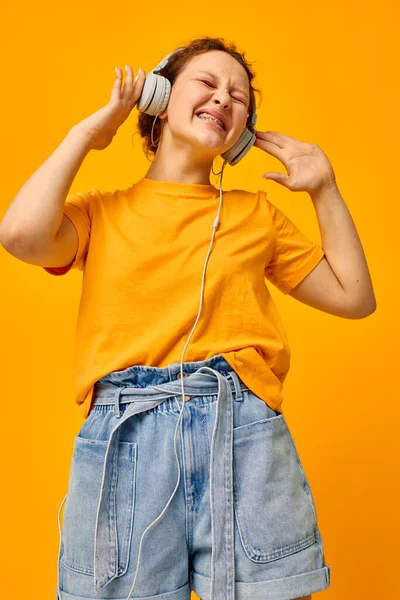 Güzel kadın sarı tişörtlü kulaklıklar eğlenceli müzik izole edilmiş arka planlar değiştirilmemiş — Stok fotoğraf
