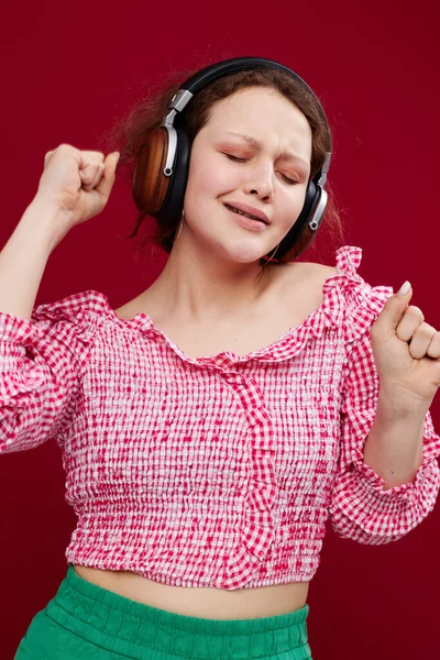 Vrolijke Vrouw Met Hoofdtelefoon Een Roze Shirt Een Rode Achtergrond — Stockfoto